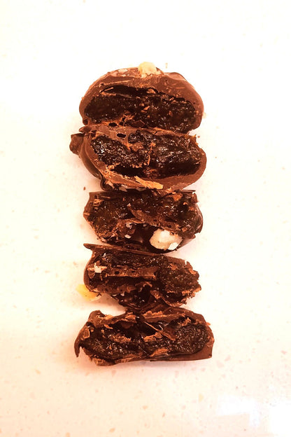 Five dark chocolate-coated prunes, split open to reveal their rich, chewy fruit interior.