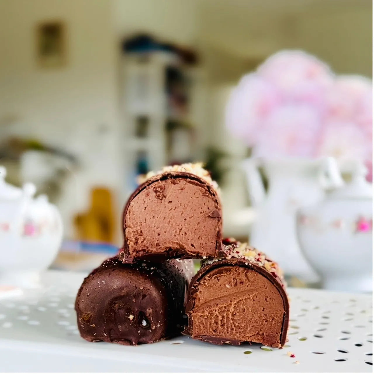 Dark chocolate dessert log halves with smooth, light brown mousse filling and crushed nuts on top.