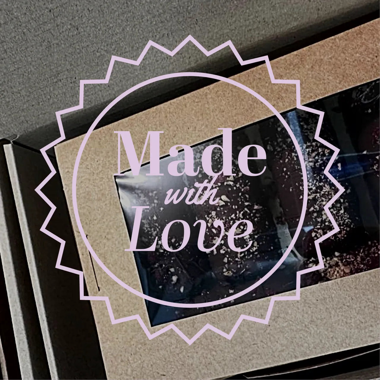 Brown cardboard box with "Made with Love" text over a clear window showing dark chocolate logs.